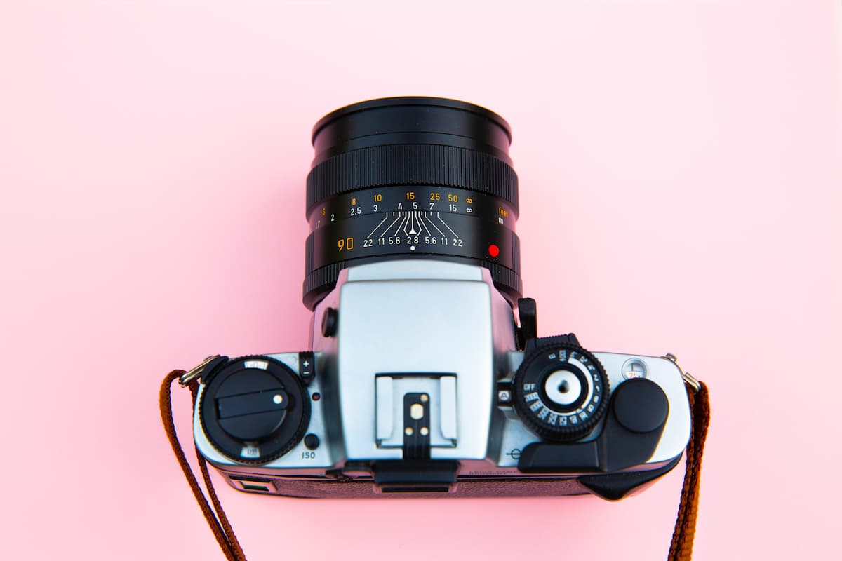 Câmera fotográfica preta e prata sob superfície plana cor de rosa