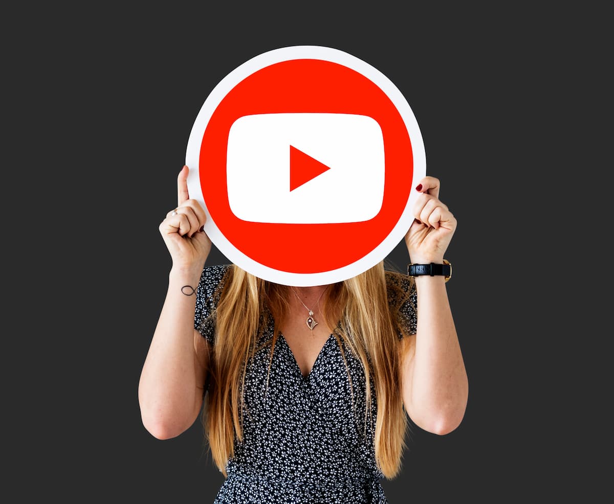 Mulher segurando a logo do YouTube na frente do rosto.