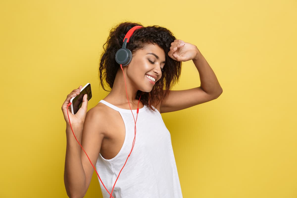 Mulher segurando celular e usando fone de ouvido enquanto curte música em uma playlist no youtube