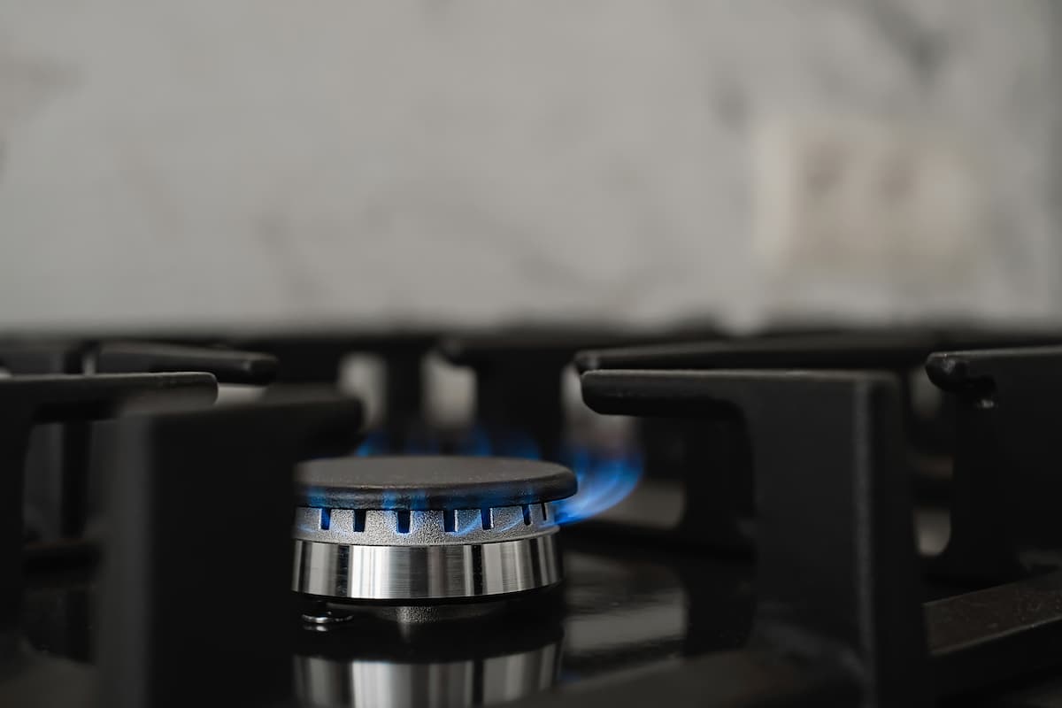 Close up em chama de gás de cozinha em uma boca de fogão acesa.