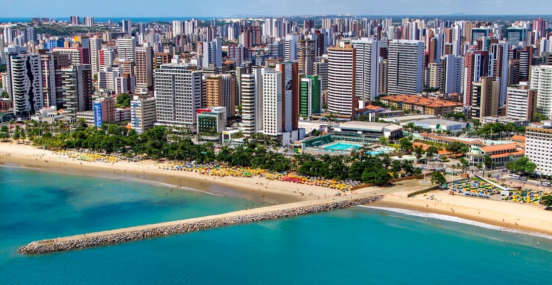 Imagem aérea da praia e cidade de Fortaleza no Ceará em dia ensolarado.