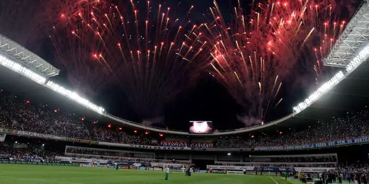 Vista panorâmica do Novo Mangueirão durante a cerimônia de inauguração com um show de fogos de artifícios no céu e arquibancada cheia de pessoas.