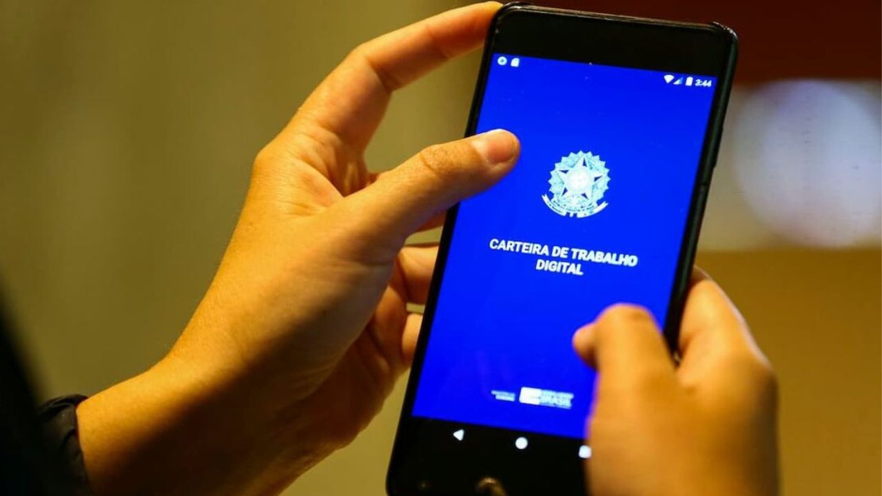 Duas mãos segurando um celular com o aplicativo da Carteira de Trabalho Digital aberto.