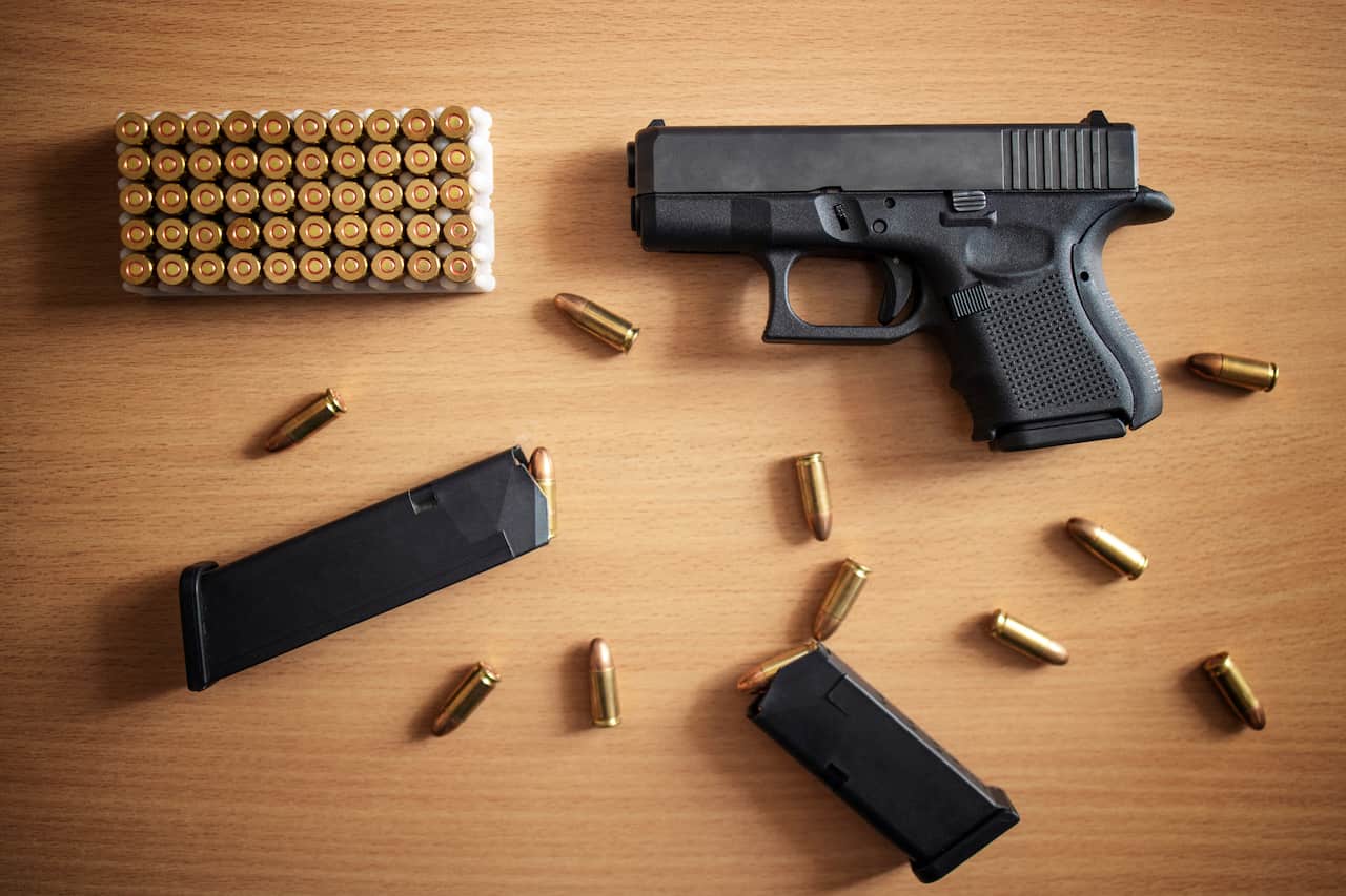 Arma e munições sobre uma mesa de madeira.