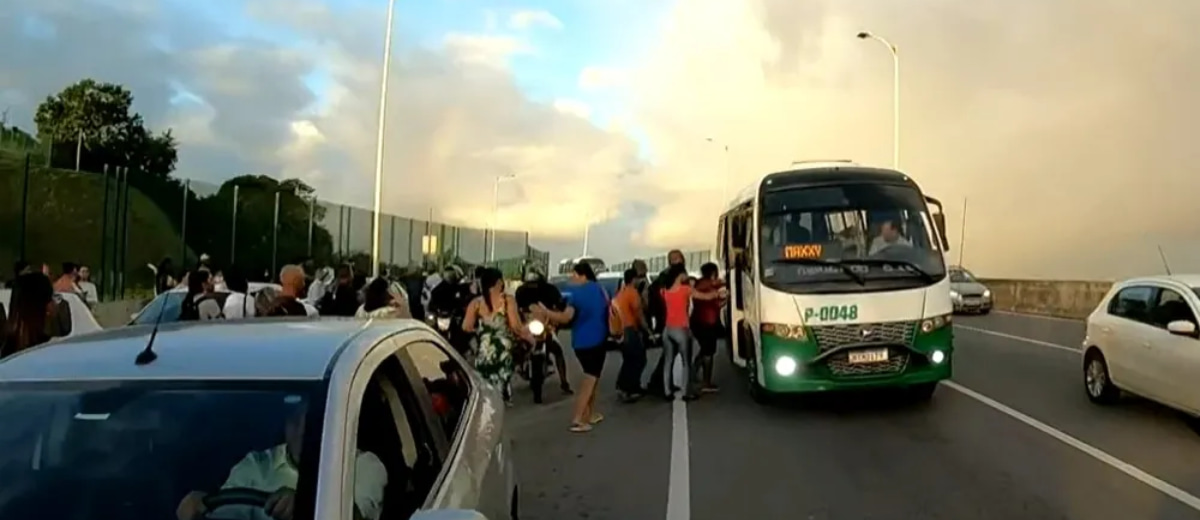 Uma enorme fila de pessoas tentando embarcar em um ônibus na rodovia.