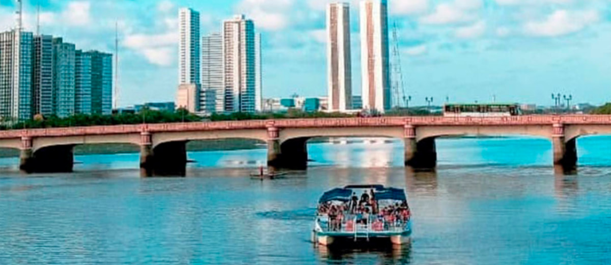 Vista panorâmica do Rio Capibaripe, onde se vê uma ponte e um catamarã navegando.