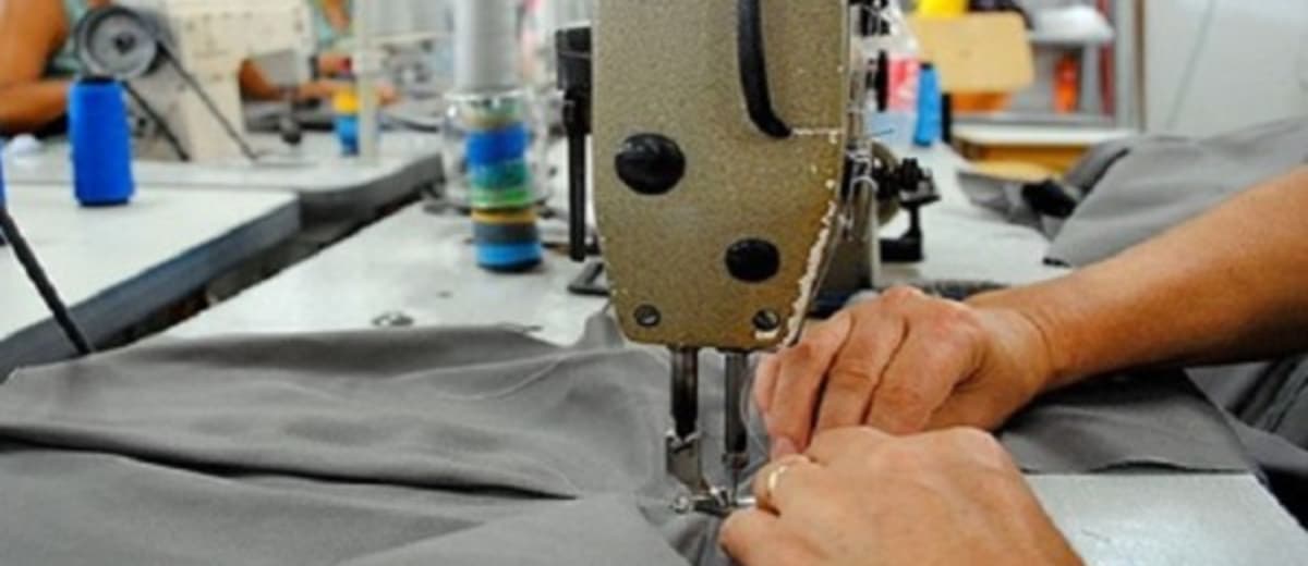 Close up de pessoa costurando roupa com uma máquina de costura.